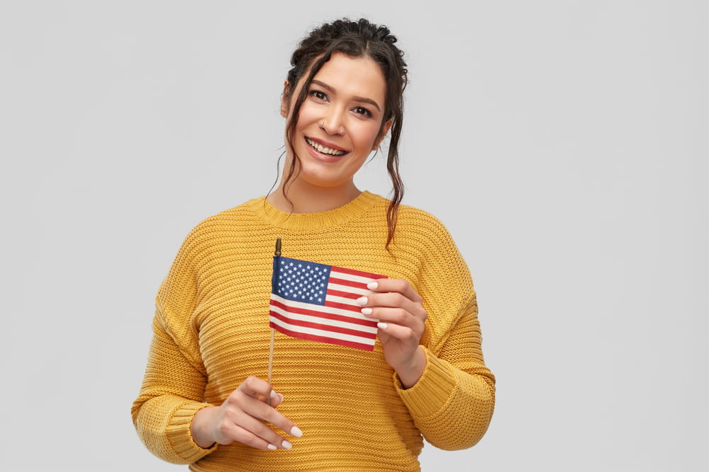 happy smiling young woman with pierced nose with flag of united states of america