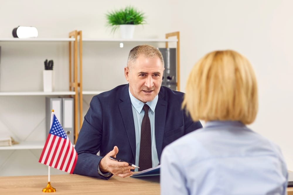 Woman sitting back in the office of the US public services or embassy having consular visa interview