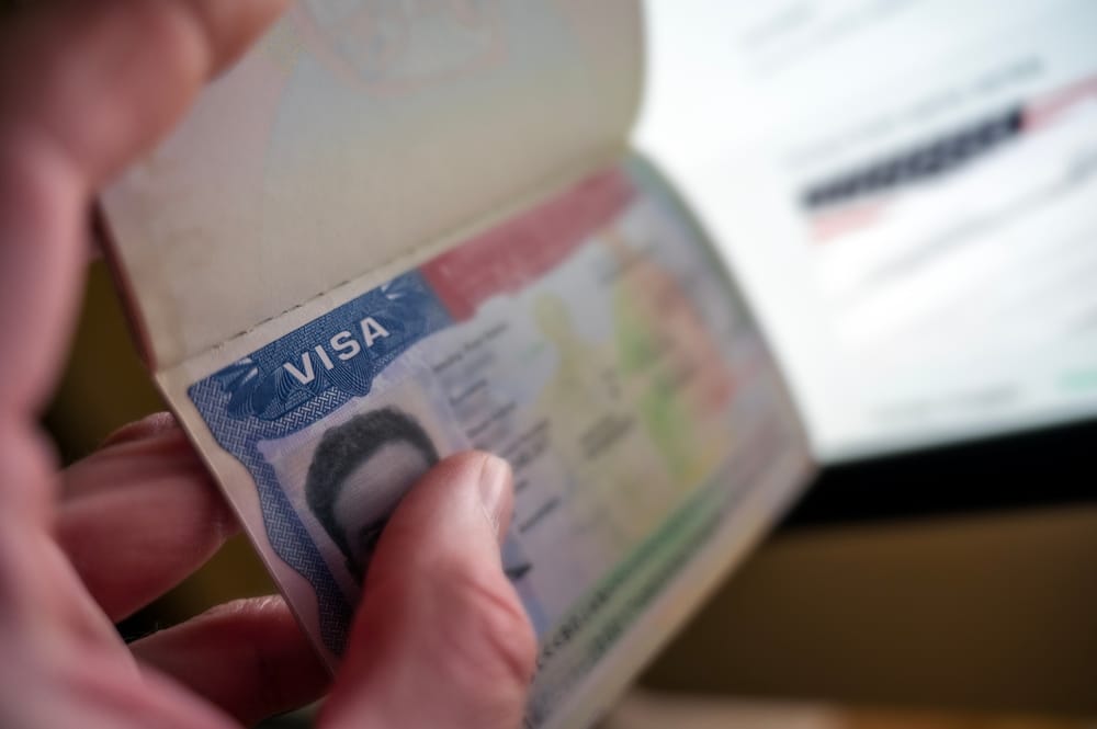 Unknown causian person holding passport with visa issued fot United States of America