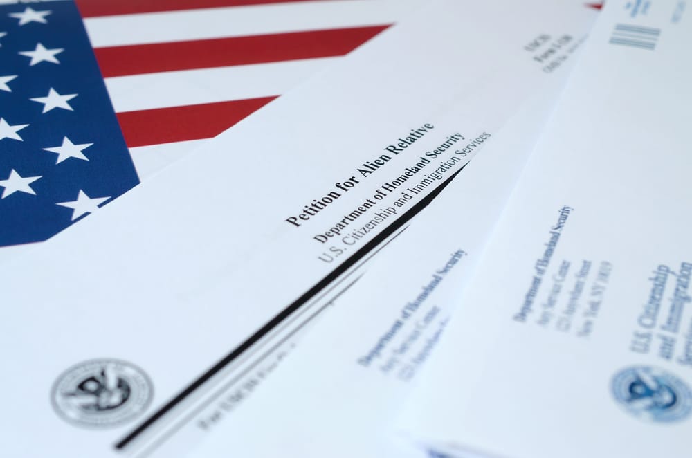 I-130 Petition for alien relative blank form lies on United States flag with envelope from Department of Homeland Security